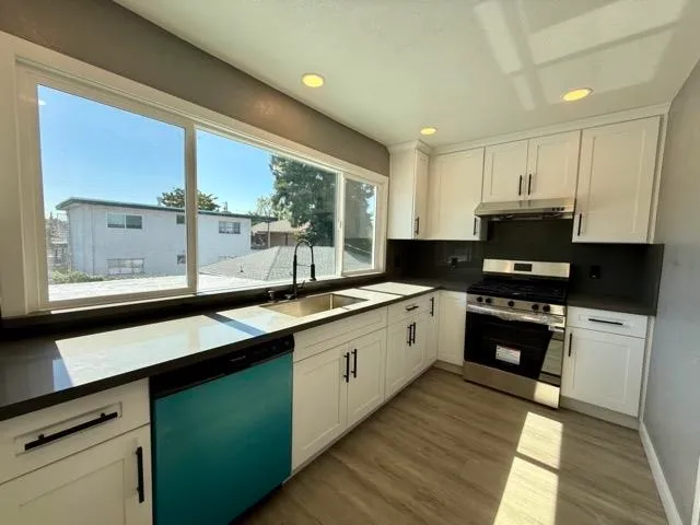 a large kitchen with granite countertop a stove and a sink