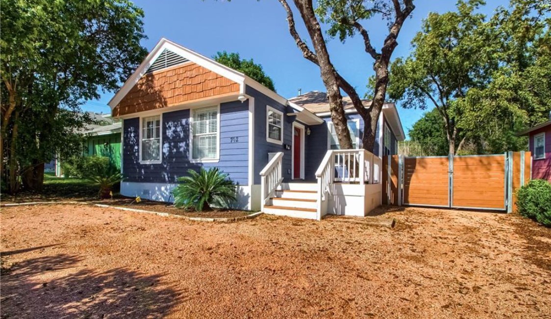 702 West N Loop Boulevard Austin, TX 78751 - Photo 2 of 23 A welcoming front porch leads to this charming blue residence, featuring natural wood siding accents.