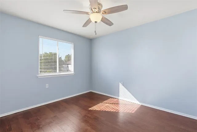 an empty room with a window and a fan