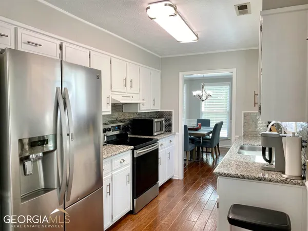 a kitchen with granite countertop a refrigerator stove and sink