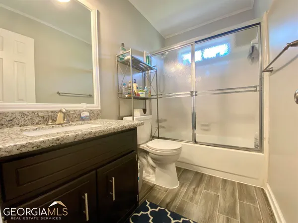 a bathroom with a granite countertop sink toilet and shower