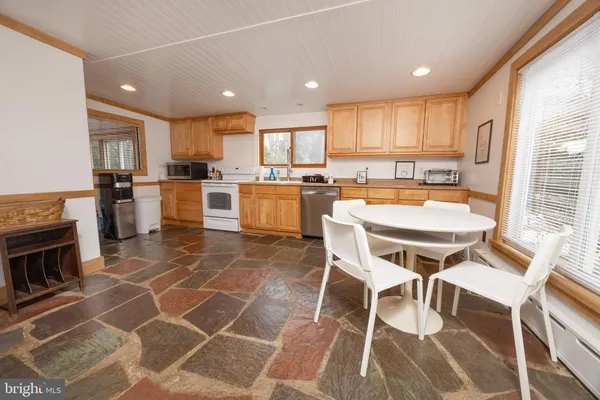 a kitchen with a dining table chairs and white appliances