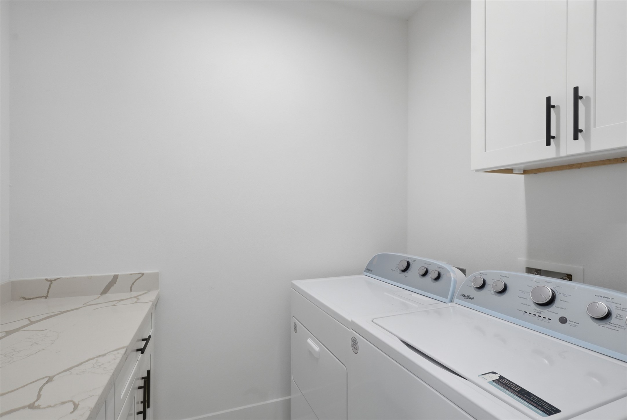 6833 Paris Street Houston, TX 77021 - Photo 12 of 23 This laundry room features a clean, modern design with white cabinetry and countertops, and includes a washer and dryer. Ample storage and workspace make it functional and efficient.