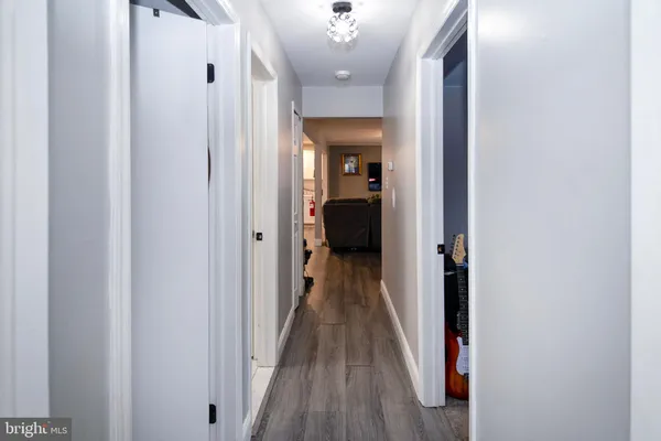 a view of a hallway with wooden floor and a bathroom