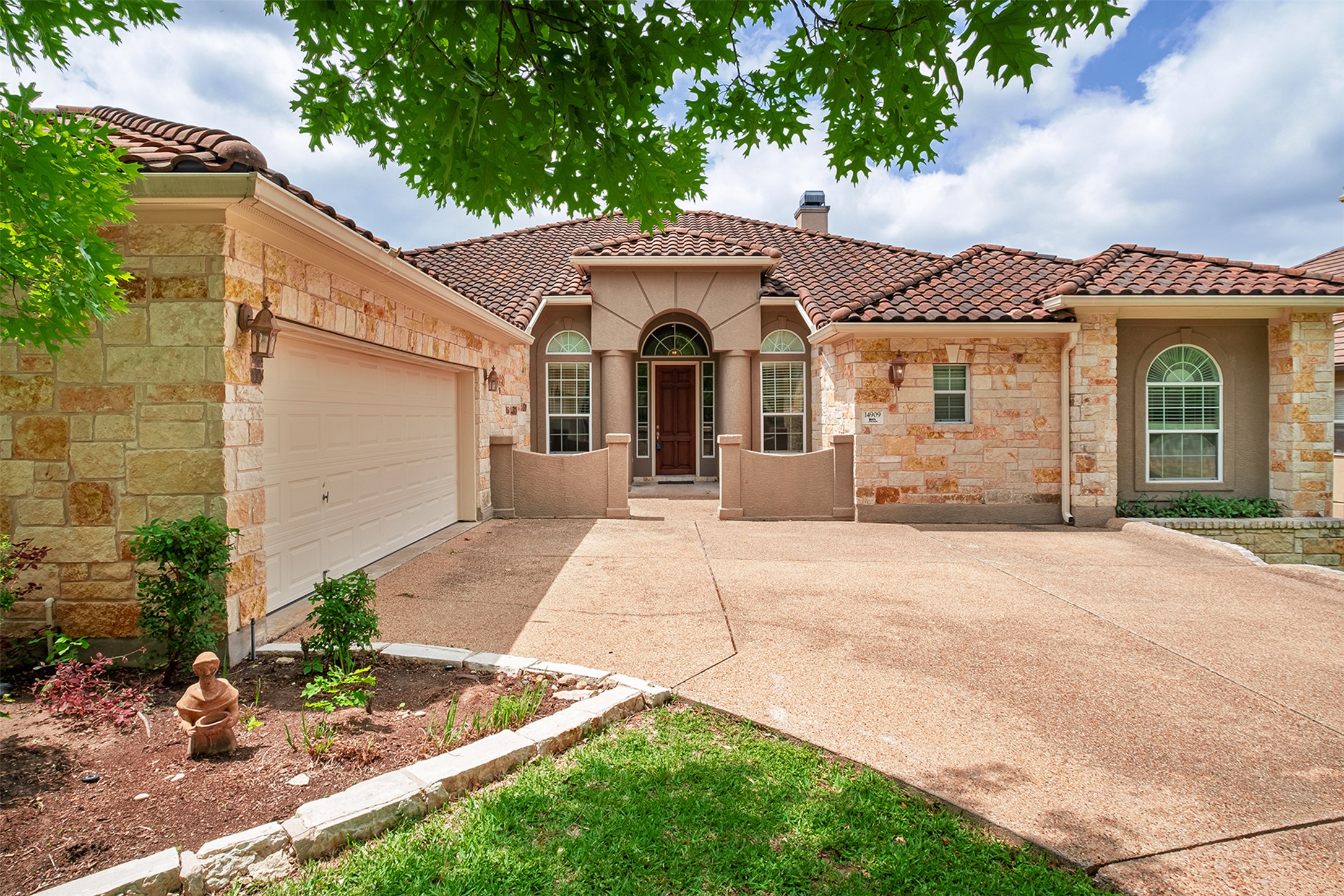 14909 Spillman Ranch Loop Austin, TX 78738 - Photo 1 of 40 Mediterranean / spanish house featuring a tiled roof, stone siding, a chimney, concrete driveway, and an attached garage
