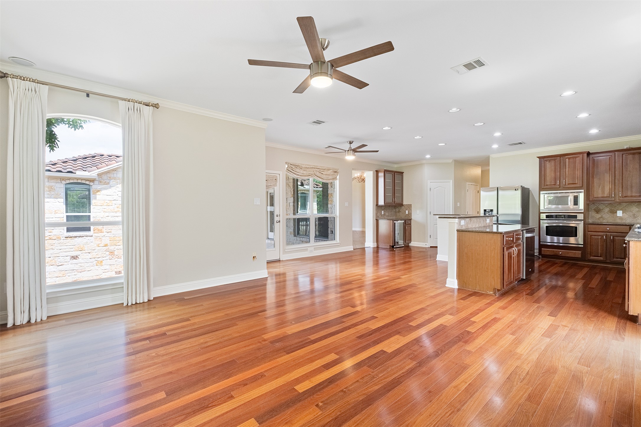 14909 Spillman Ranch Loop Austin, TX 78738 - Photo 13 of 40 Kitchen with visible vents, decorative backsplash, a ceiling fan, crown molding, and appliances with stainless steel finishes