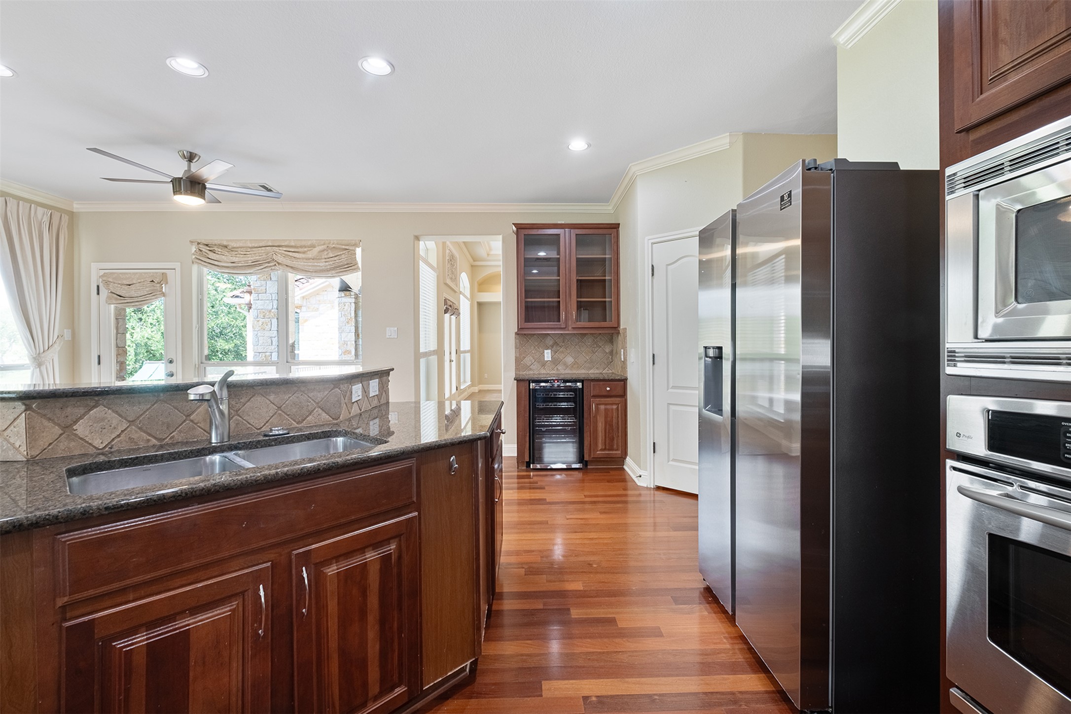 14909 Spillman Ranch Loop Austin, TX 78738 - Photo 15 of 40 Kitchen with wine cooler, a sink, backsplash, appliances with stainless steel finishes, and ornamental molding