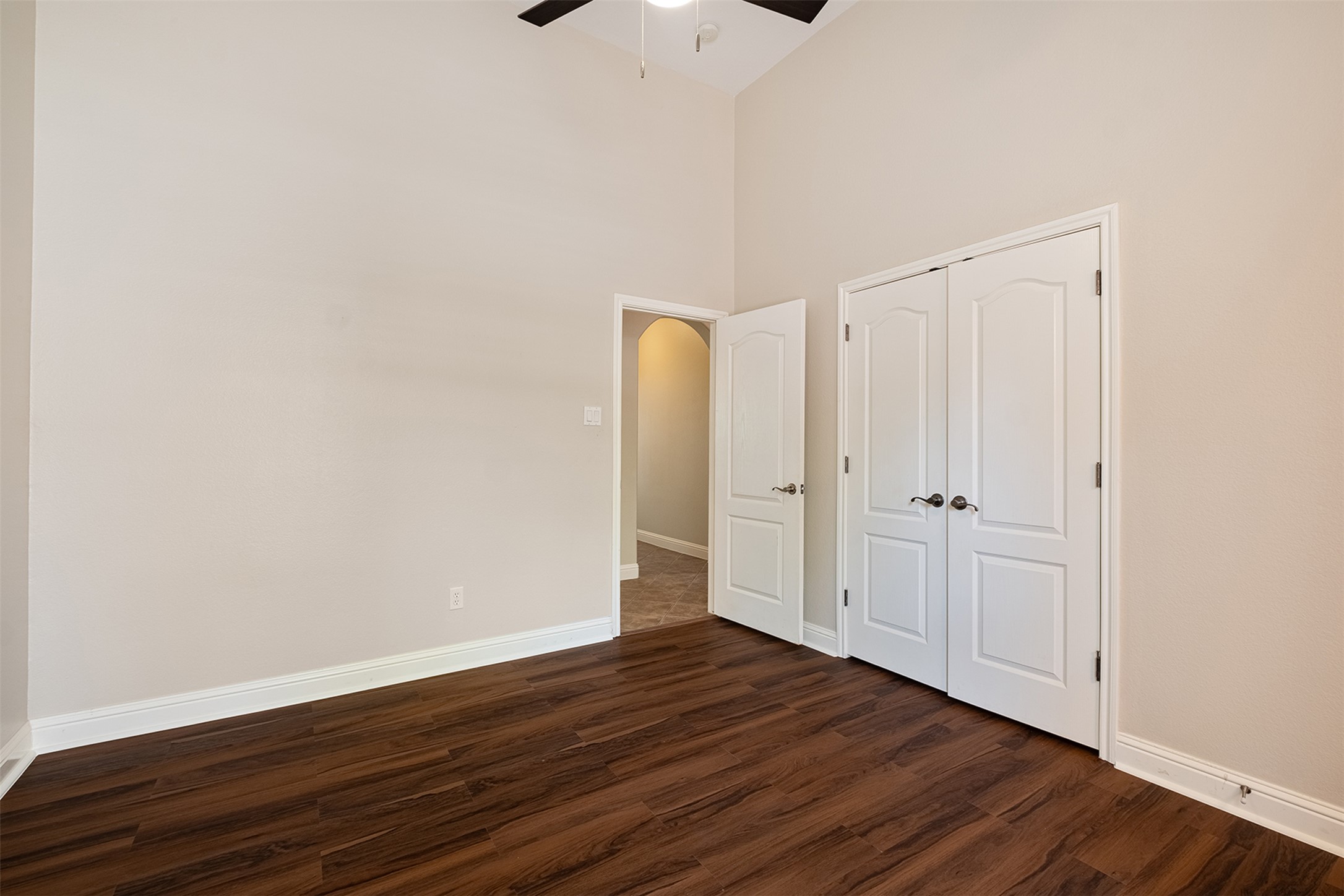 14909 Spillman Ranch Loop Austin, TX 78738 - Photo 25 of 40 Unfurnished bedroom featuring dark wood-type flooring, arched walkways, a high ceiling, and baseboards