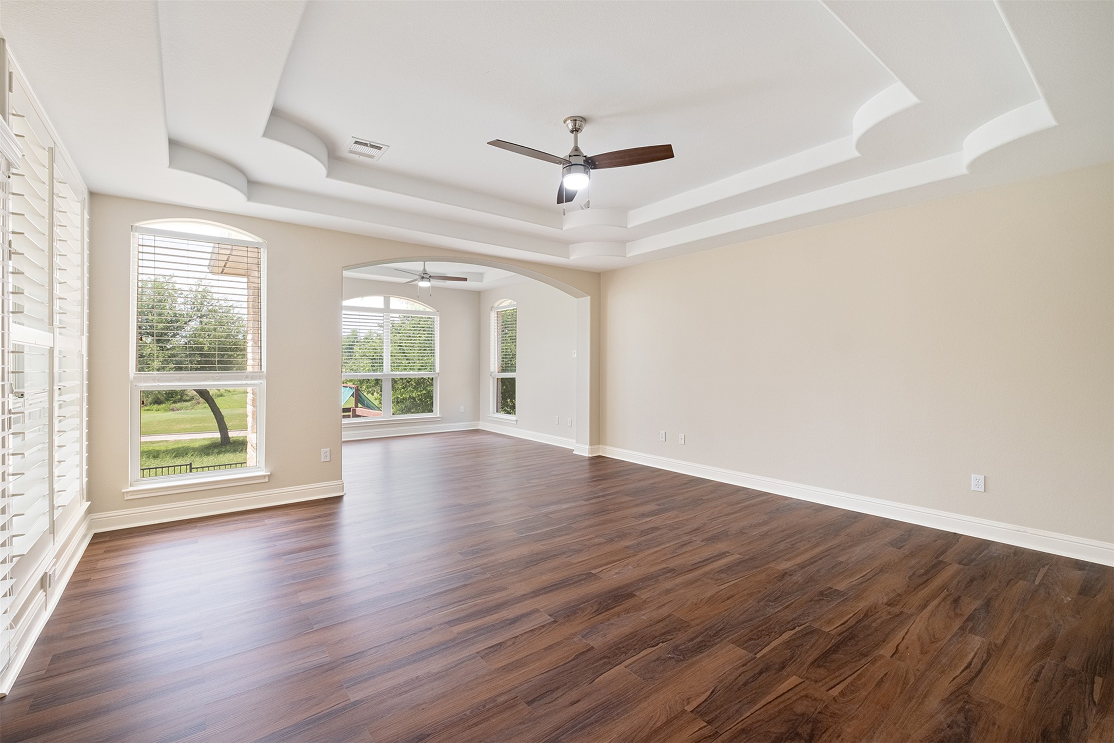 14909 Spillman Ranch Loop Austin, TX 78738 - Photo 29 of 40 Spare room with a tray ceiling, visible vents, a ceiling fan, baseboards, and dark wood-style flooring