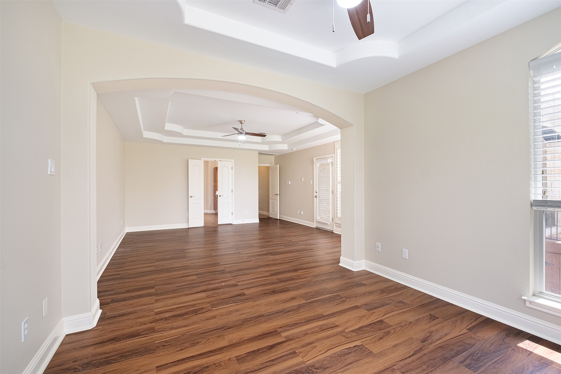 14909 Spillman Ranch Loop Austin, TX 78738 - Photo 31 of 40 Spare room featuring dark wood finished floors, a raised ceiling, a ceiling fan, arched walkways, and baseboards