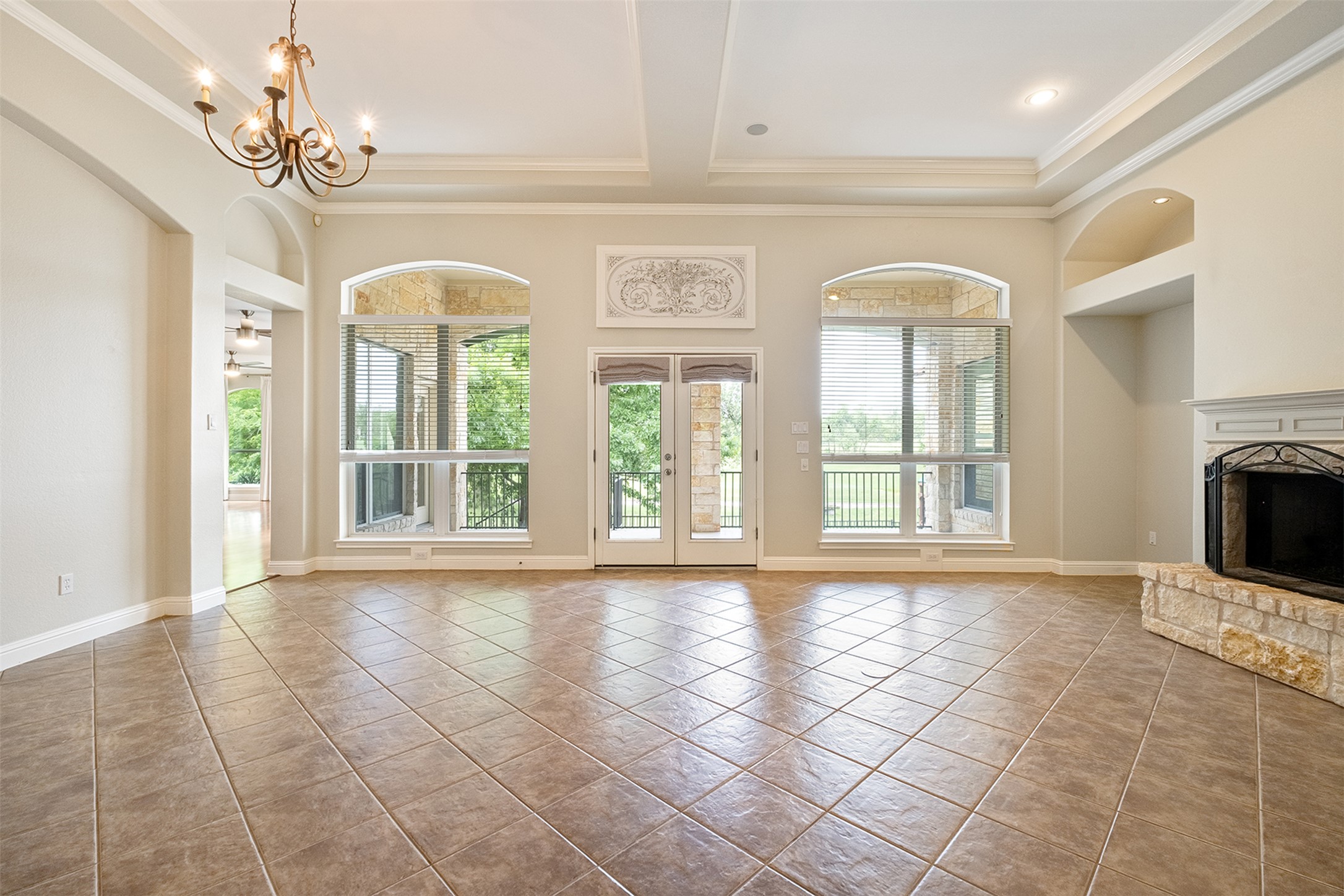 14909 Spillman Ranch Loop Austin, TX 78738 - Photo 5 of 40 Unfurnished living room with an inviting chandelier, ornamental molding, tile patterned flooring, and a fireplace with raised hearth
