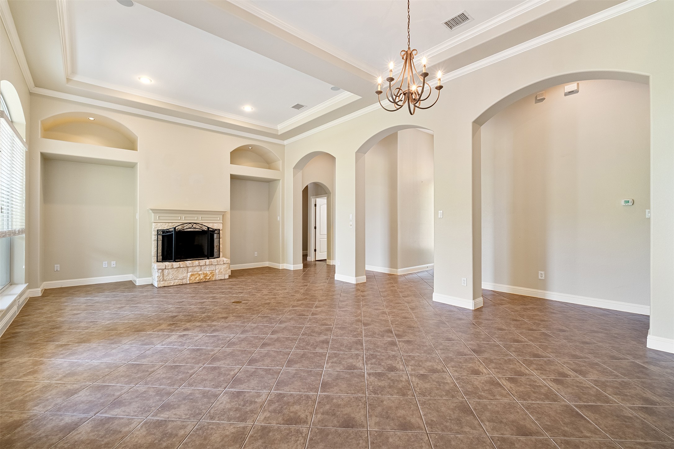 14909 Spillman Ranch Loop Austin, TX 78738 - Photo 6 of 40 Unfurnished living room featuring a tray ceiling, visible vents, ornamental molding, a fireplace, and built in shelves