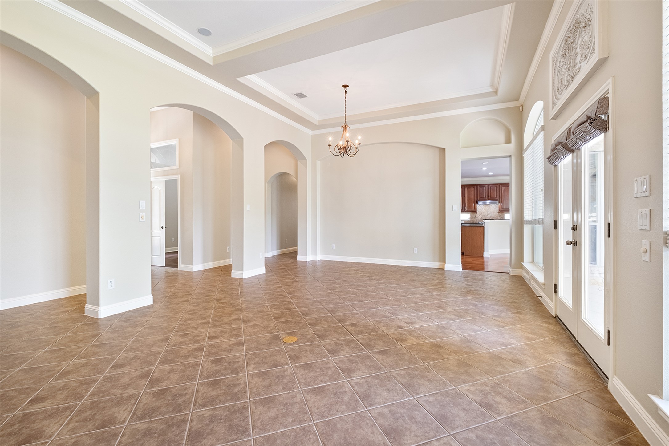 14909 Spillman Ranch Loop Austin, TX 78738 - Photo 7 of 40 Unfurnished room featuring a tray ceiling, arched walkways, baseboards, a notable chandelier, and crown molding