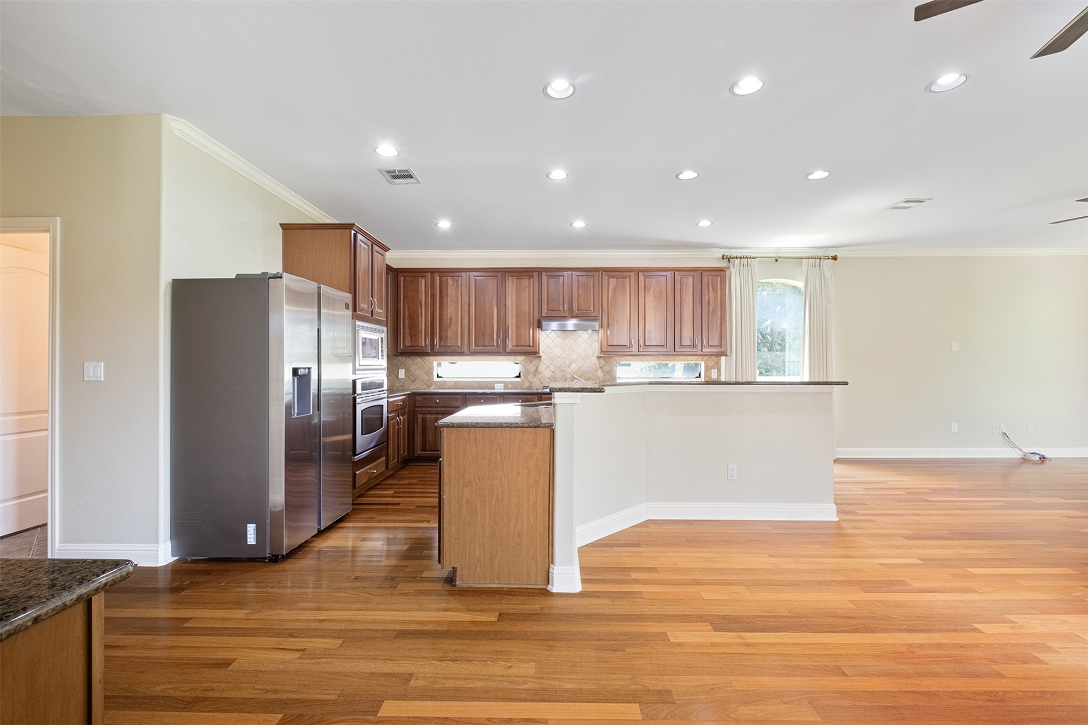 14909 Spillman Ranch Loop Austin, TX 78738 - Photo 10 of 40 Kitchen featuring stainless steel appliances, ornamental molding, decorative backsplash, light wood-style flooring, and ceiling fan