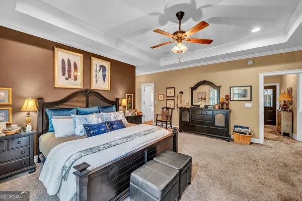 a bedroom with a bed a dresser and a chandelier