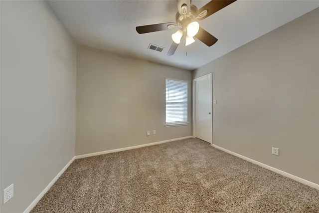 an empty room with a chandelier fan and windows