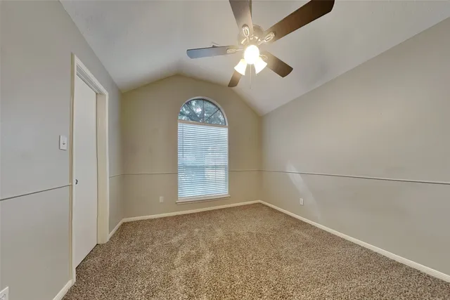an empty room with a chandelier fan and windows