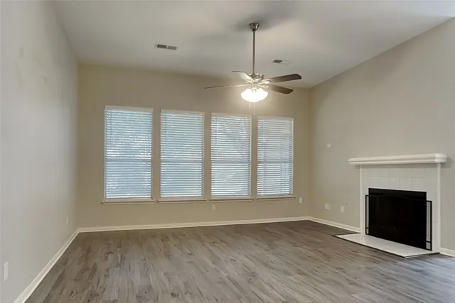 a view of an empty room with wooden floor fireplace and a window