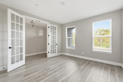 an empty room with wooden floor and windows