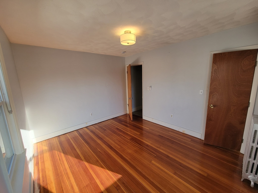 100 Medford Street, Unit 2 Malden, MA 02148 - Photo 14 of 29 a view of an empty room with wooden floor and window