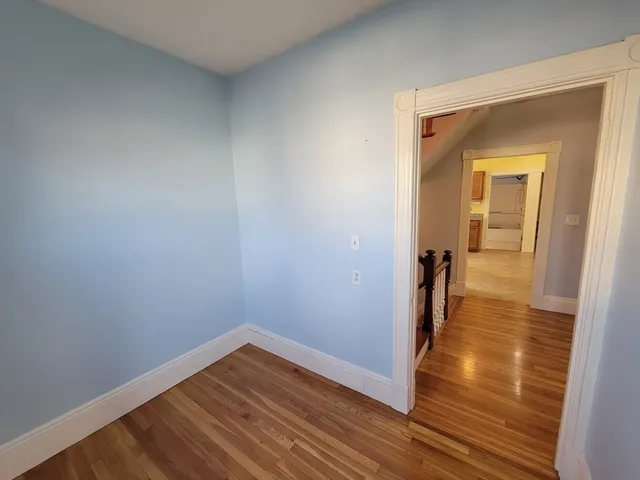 a view of a room with wooden floor and a hallway