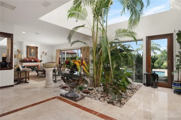 a room with lots of flower plants and glass door