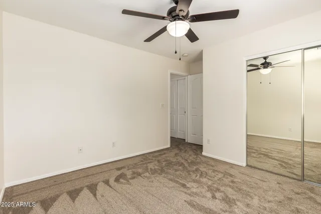 an empty room with a ceiling fan and a window