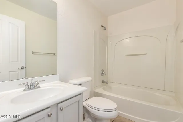 a bathroom with a bathtub shower sink vanity mirror and toilet