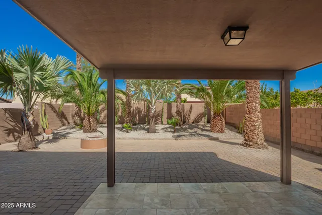 a view of a backyard with table and chairs potted plants and large tree