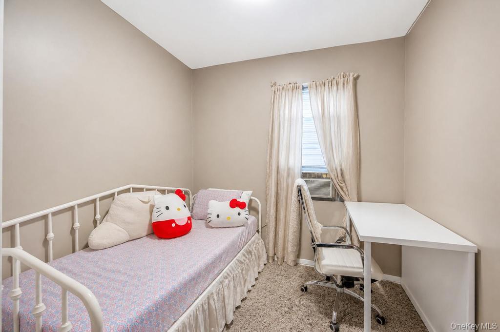 89-13 84th Street Queens, NY 11421 - Photo 24 of 34 Bedroom featuring neutral wall paint, carpet flooring, a window with sheer curtains, and a built-in air conditioning unit
