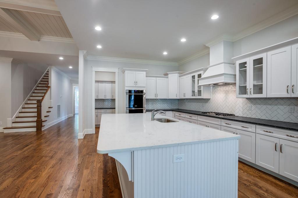 5908 Pinewood Road Franklin, TN 37064 - Photo 12 of 30 a kitchen with stainless steel appliances granite countertop a sink a stove a refrigerator and white cabinets with wooden floor