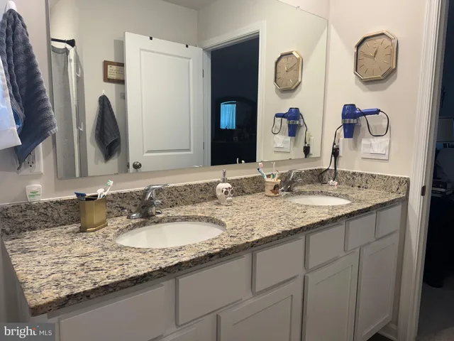 a bathroom with a granite countertop double vanity sink and a mirror