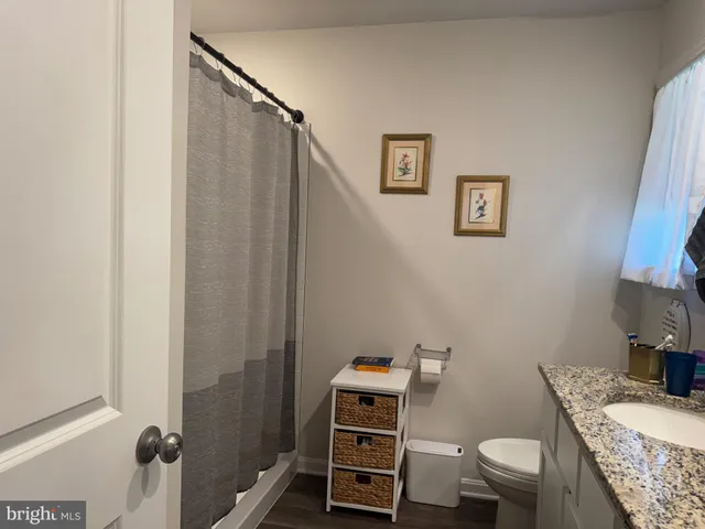 a bathroom with a granite countertop sink toilet and a mirror