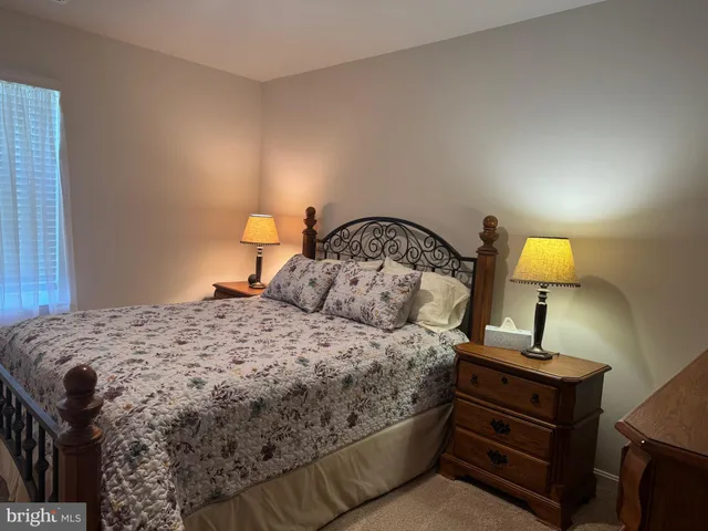 a bedroom with a bed and a lamp on dresser
