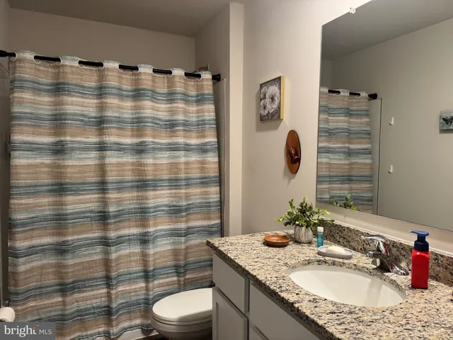 a bathroom with a granite countertop sink mirror vanity and toilet