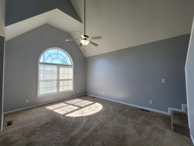an empty room with windows and ceiling fan