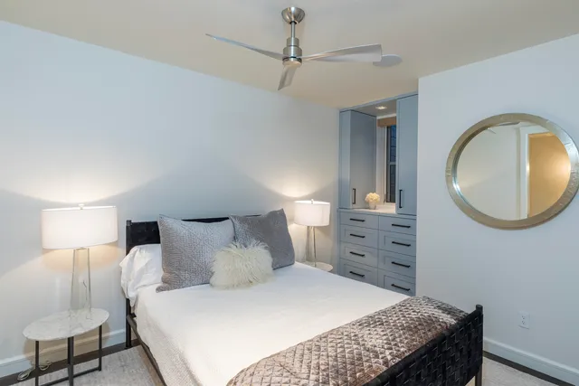 a bedroom with a bed and a lamp on dresser