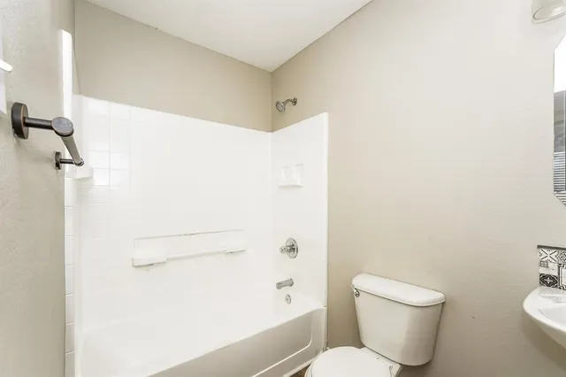 a white toilet sitting next to a bath tub