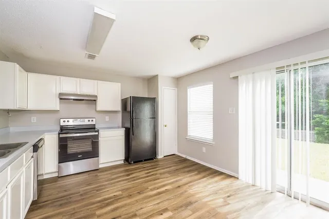 a kitchen with granite countertop a refrigerator and a stove top oven
