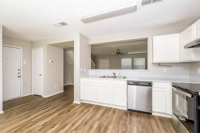 a kitchen with stainless steel appliances a sink and wooden floor
