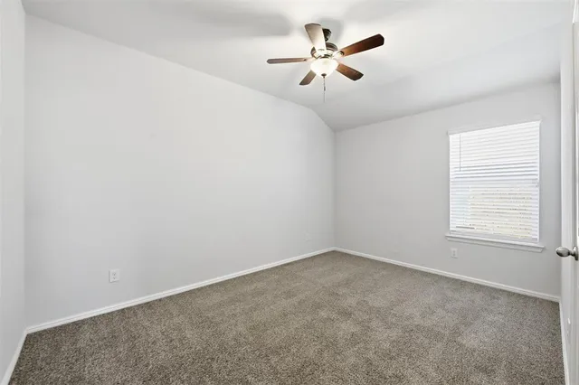 an empty room with a window and ceiling fan