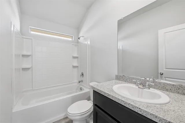 a bathroom with a granite countertop sink a toilet and shower