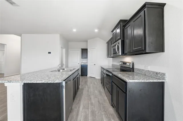 a kitchen with granite countertop stainless steel appliances a sink stove and cabinets