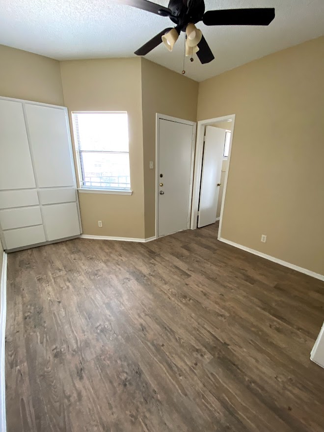 3316 Guadalupe Street, Unit 212 Austin, TX 78705 - Photo 2 of 22 an empty room with wooden floor chandelier fan and windows