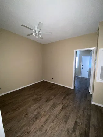 a view of an empty room with wooden floor and cabinets