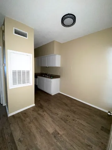 an empty room with wooden floor cabinet and windows