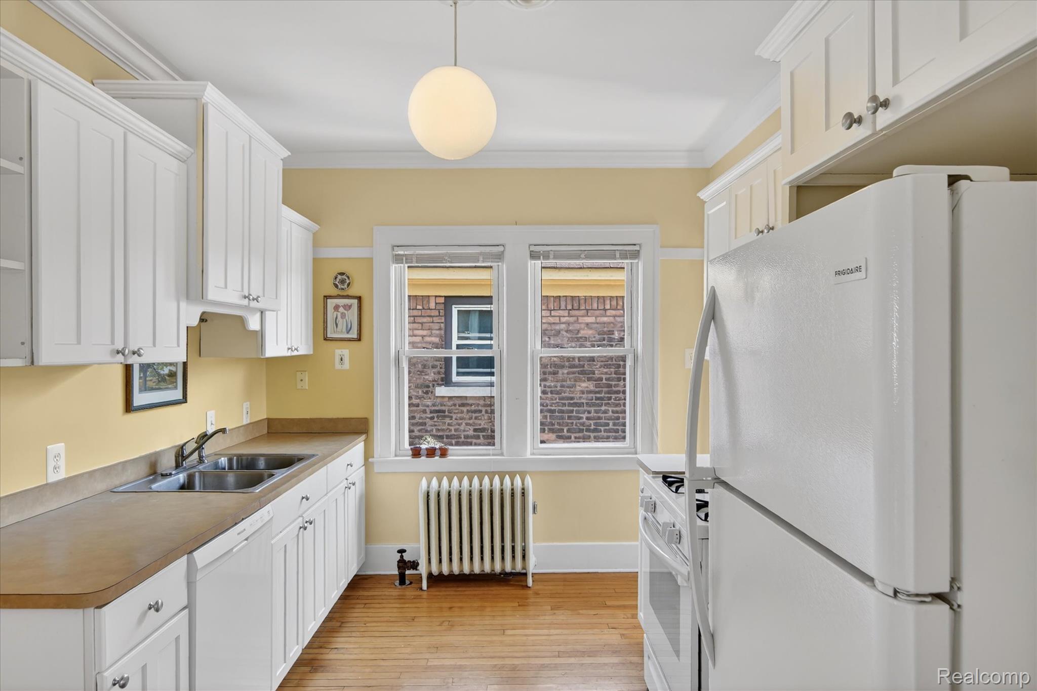 925 Nottingham Road Grosse Pointe, MI 48230 - Photo 18 of 46 Kitchen with white appliances, white cabinets, light wood-style floors, radiator, and light countertops