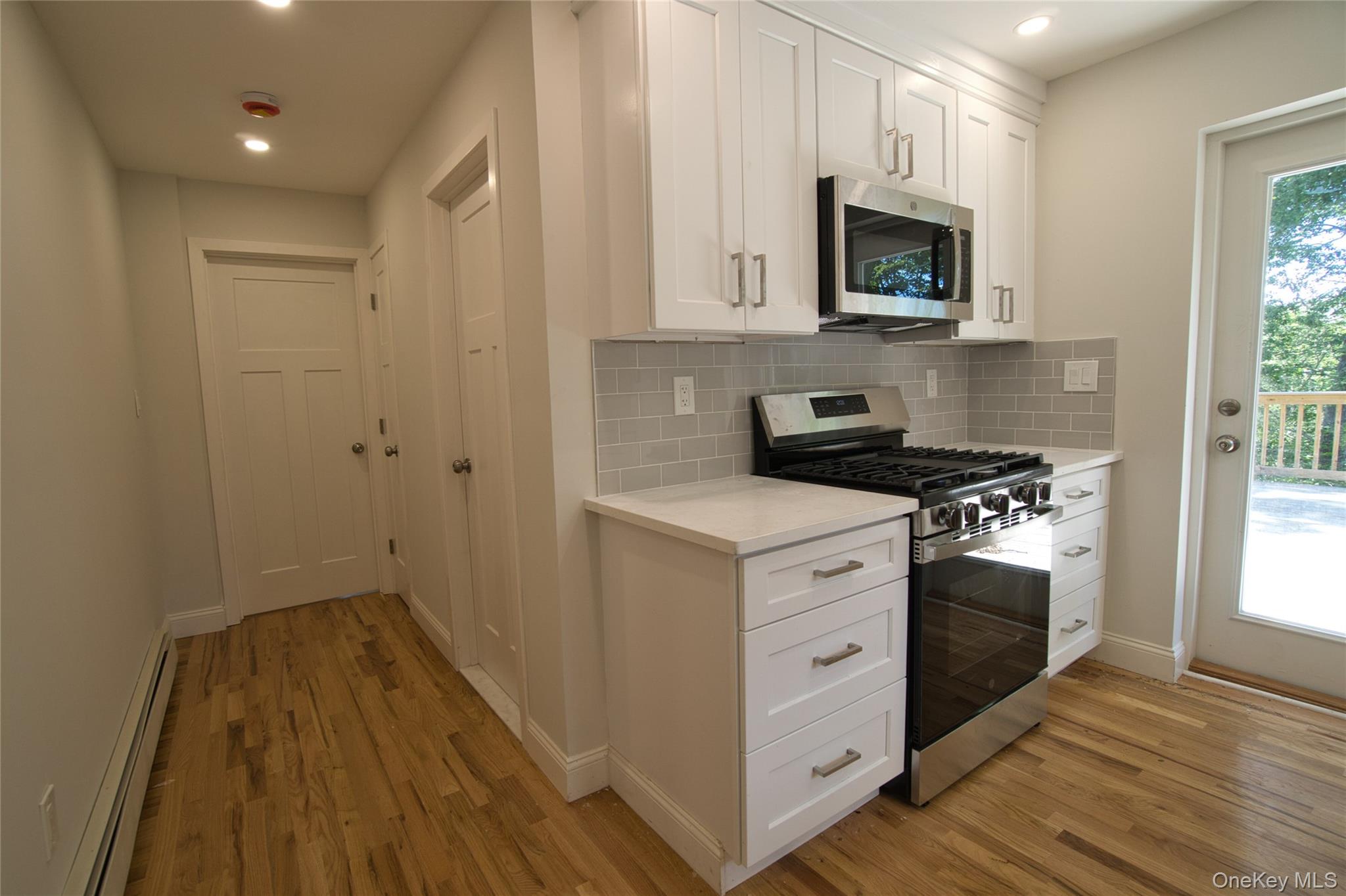 29 Overlin Road Patterson, NY 12563 - Photo 7 of 16 Kitchen featuring white shaker cabinetry, stainless steel appliances, light subway tile backsplash, and light-toned countertops