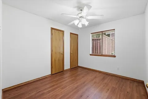 an empty room with wooden floor fan and windows