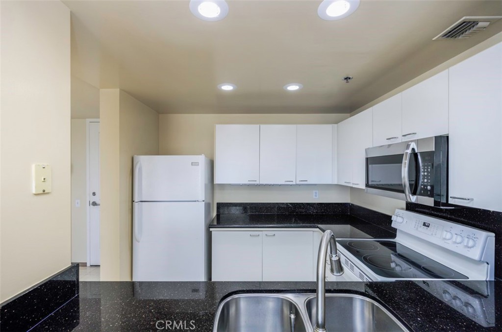 525 East Seaside Way, Unit 704 Long Beach, CA 90802 - Photo 11 of 38 a kitchen with a refrigerator and a stove top oven